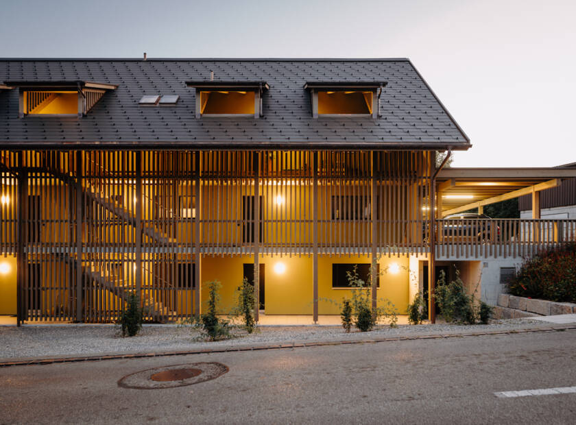 Maison multifamiliale en forme de maison en bois et avec toit solaire le jour et au crépuscule Habitat collectif, Hüttwilen, CH