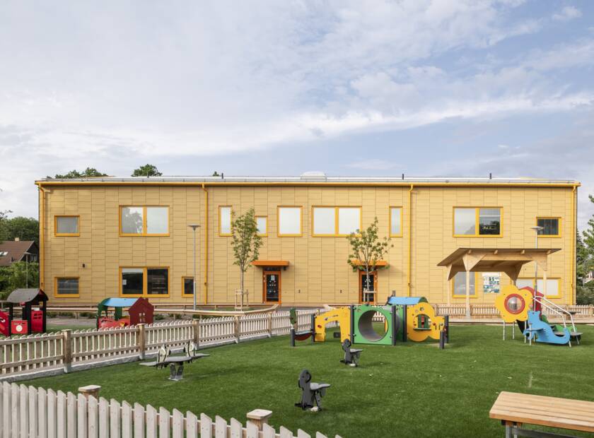 The preschool is designed according to the Miljöbyggnad Silver standard and the building is now also certified. Façades of solid-coloured yellow façade panels in a special assembly of overlapping panels. Framtidens Förskola Skåpbilen SISAB, Stockholm, Sweden