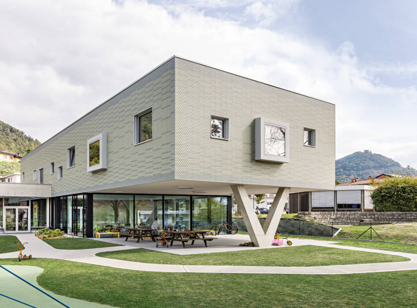 Un bâtiment moderne au design unique. Le bâtiment est de forme rectangulaire et la façade est en ardoise de façade "Eternit". Öffentliche Bauten, Jardin d'enfants, Castel San Pietro, CH